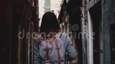 后景女商人带着背包，穿着时髦的西装，在威尼斯的黑暗街道上行走，意大利慢动作。